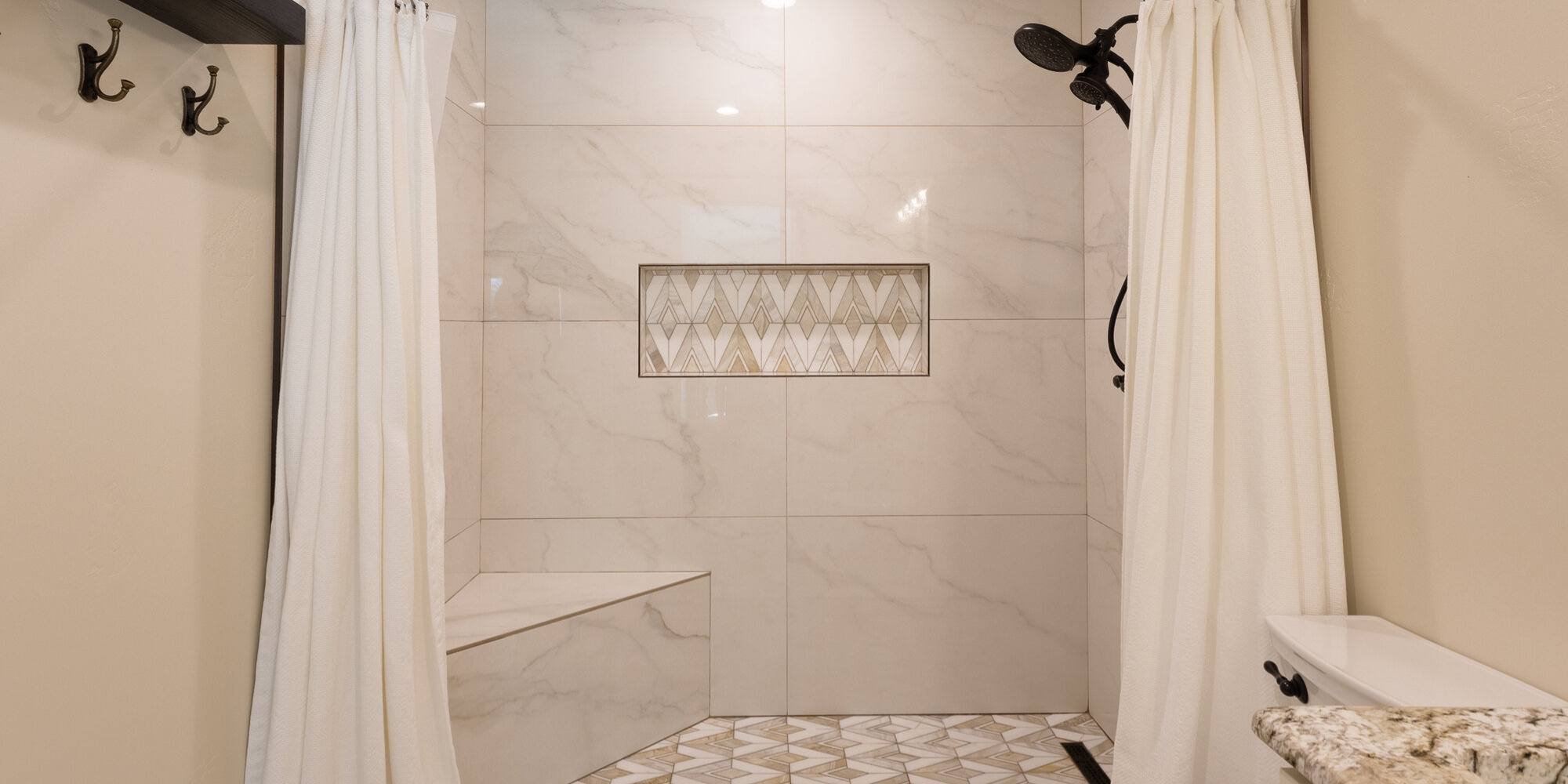 Full shower view with white curtain and decorative tilework by M&G Construction in Reno home.