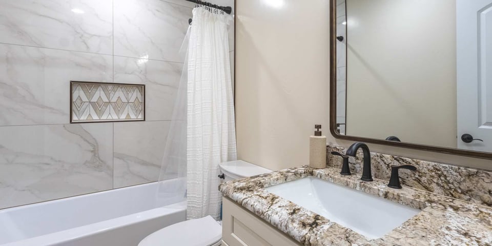 Image of bathroom remodel with bathtub shower combo, stone vanity countertop, and decorative tile in Reno, NV by M&G Construction