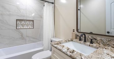 Image of bathroom remodel with tub shower combo, granite vanity, and marble tile in Reno, NV by M&G Construction