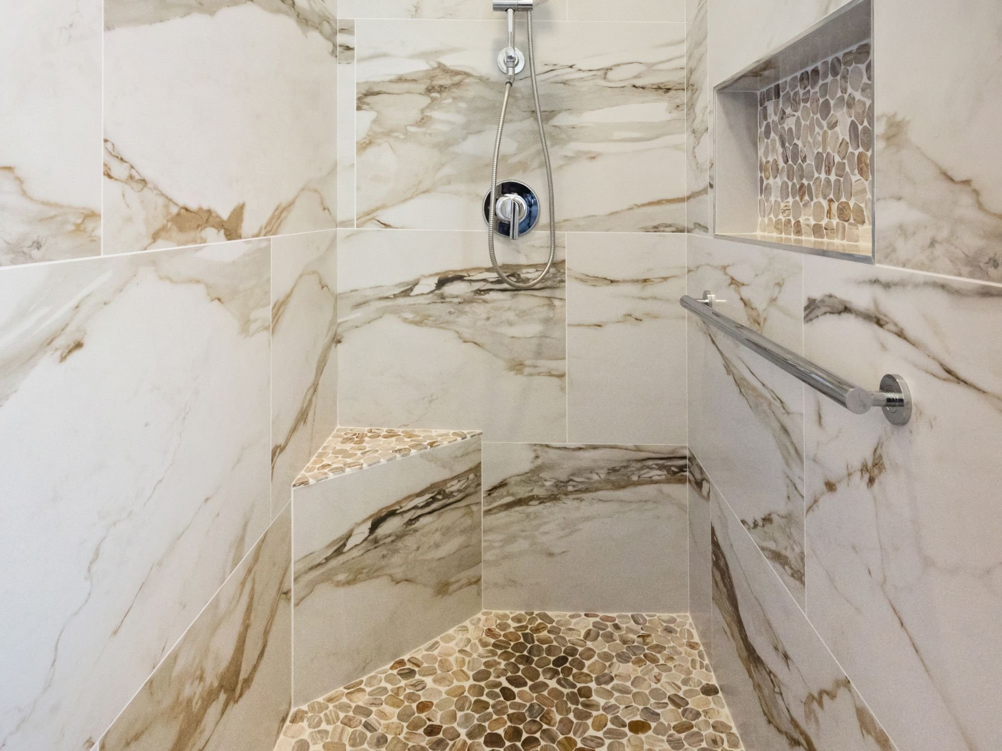 Detailed view of a walk-in shower in a bathroom remodel with pebble mosaic tile shower pan, nice, and corner bench in Northwest Reno by M&G Construction Detailed view of a walk-in shower in a bathroom remodel with pebble mosaic tile shower pan, nice, and corner bench in Northwest Reno by M&G Construction