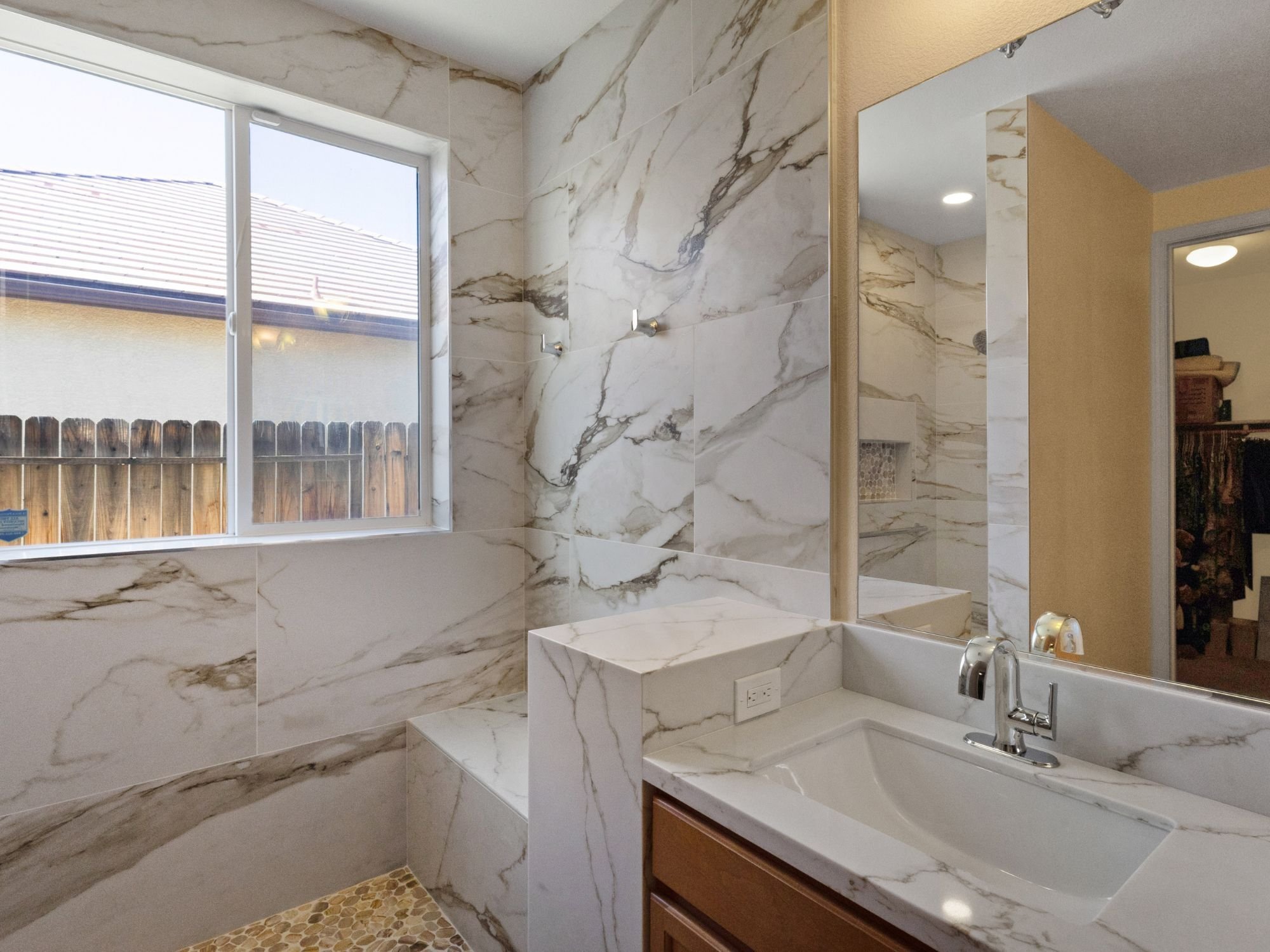 Primary bathroom remodel with a dedicated dry-off area, natural light, and marble-like stone and tile in Northwest Reno by M&G Construction