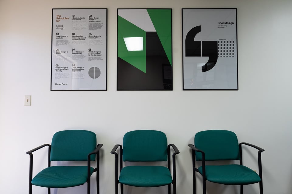 Waiting area with green chairs and framed design posters at M&G Construction’s custom home office in Carson City, Nevada.
