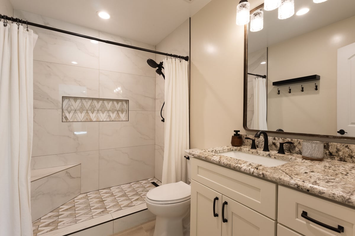 Renovated bathroom featuring granite vanity and walk-in shower with accent tile, built by M&G Construction, Reno.