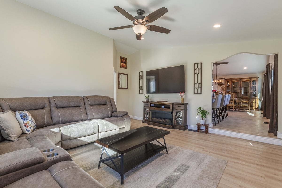Stylish living room with sectional sofa, wall-mounted TV, and open dining space in M&G Construction custom home, Reno, NV.